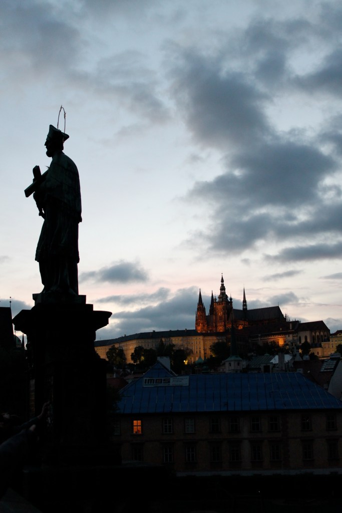 Prague Castle illuminated, with one the most famous statue on St. Charles Bridge up front